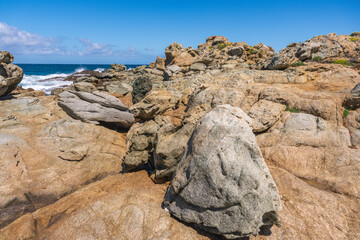 Bright turquoise waters splash against the rugged beach cliffs in Lile Rousse Corsica France