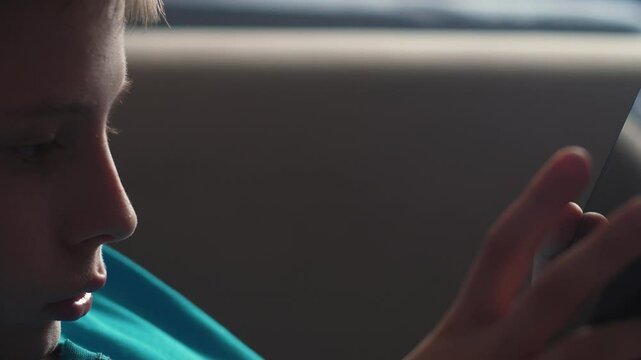 Caucasian boy 11-12 years old eagerly using a tablet computer indoors, teenager using a gadget at home for video editing or content creation