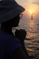 Christian woman praying in the sky with cross and light