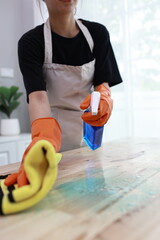 A cheerful young woman confidently cleans her apartment, embracing weekend chores with a smile,...