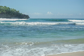 Calm Waves Approach the Beach with Green Cliffs on the Side at wawaran beach pacitan east java indonesia