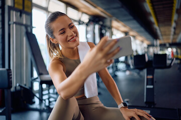 Happy athlete taking selfie during her sports training in gym.