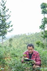Millennial agricultural worker seated rows of chili trees combining hands on plant inspection with real time digital monitoring symbol of future forward agriculture empty copy space