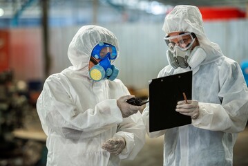 Male inspector team investigate danger chemical gas leak spill with safety face mask PPE suit in...