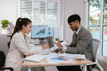 Business professionals analyzing investment graphs and financial charts on laptops during a strategic meeting in a modern office environment.