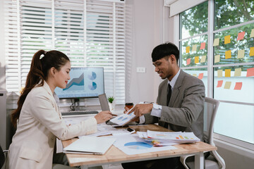 Business professionals analyzing investment graphs and financial charts on laptops during a strategic meeting in a modern office environment.