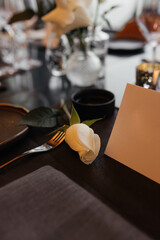 White rose and blank paper card on a table. Minimalistic floral composition with space for text. Romantic, elegant and natural atmosphere for celebration, wedding or message.