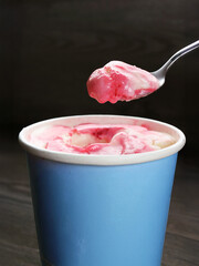 Spoon scooping delectable strawberry yogurt ice cream
