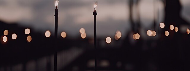 Three lit candles in the foreground with out-of-focus lights in the background