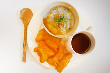 Traditional Thai breakfast with rice porridge, deep-fried dough sticks, and a hot drink. Comforting...