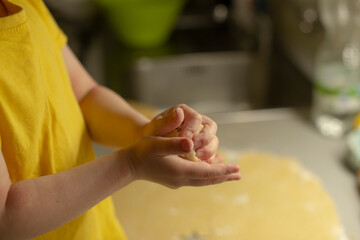A young child is enthusiastically shaping and kneading dough with their small hands on a kitchen...