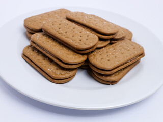 Stack of rectangular biscuits with sugar topping neatly arranged on a white plate, isolated on a white background