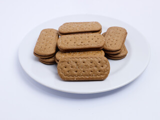 Stack of rectangular biscuits with sugar topping neatly arranged on a white plate, isolated on a white background