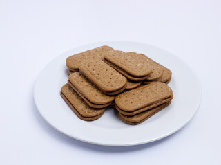 Stack of rectangular biscuits with sugar topping neatly arranged on a white plate, isolated on a white background
