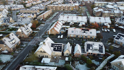 Neighborhood houses with solar panels snow on roof during winter. Street in a residential area...