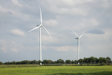 Landscape photo of two wind turbines in meadow farming field. Green renewable energy, global warming, climate change, sustainability, farm land concept.