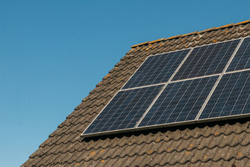 Fototapeta premium Solar panels on roof. Close up with blue summer sky backrground. Sustainability, eco-friendly technology powered by the sun. Renewable energy solutions building house in neighbourhood.