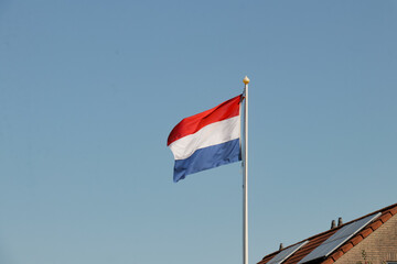Dutch flag on white pole, Netherlands Holland. Garden rooftop national flagging at home. House in neighborhood.