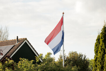 Dutch flag red white blue stripe pole blue sky.