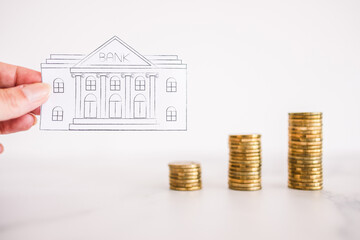 bank icon next to increasing stacks of coins, increasing interest rates and fees or growing your savings