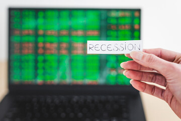 recession and stock market volatility after the pandemic, Recession text in front of computer screen with financal markets results