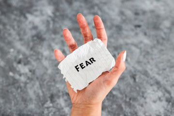 hand holding Fear text on scrunched up piece of paper, psychology concept