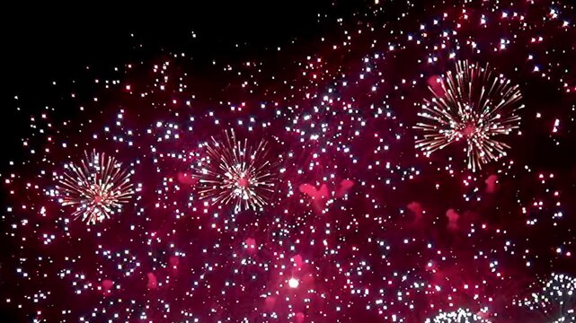 A stunning array of vibrant fireworks illuminates the night sky, marking the joyous arrival of the New Year with bursts of color and dazzling patterns, captivating the audience below.