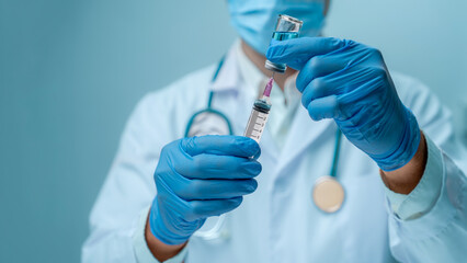 Doctor in blue glove and face mask is filling syringe with vaccine. It represents healthcare,...
