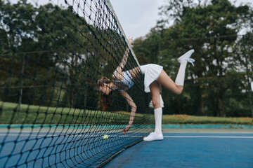 Energetic young female tennis player in sportswear displaying dynamic motion on a tennis court,...