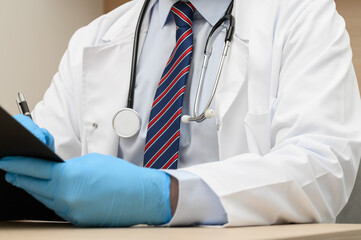 Lekarz siedzący za biurkiem w czasie wizyty pacjenta, wywiad chorobowy i wypisywanie recepty, diagnostyka, 