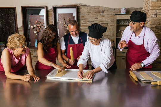 Chefs showing how to roll dough during cooking course