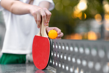 Table tennis, yellow ball and rackets close up in the hands of a girl, outdoor sport leisure activity, copyspace for text