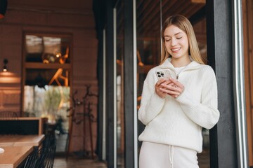Young woman using mobile phone while leaning on a door frame