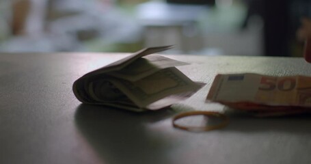 A variety of banknotes spread across a table might be seen during the process of a cash transaction taking place - Powered by Adobe