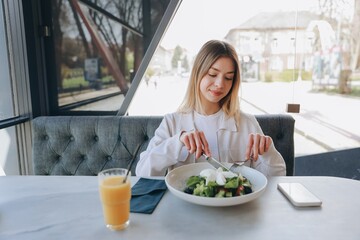 Young woman eating healthy salad in a restaurant