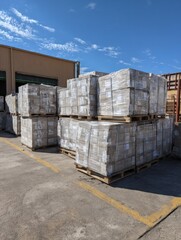 Crates of Tile Adhesive on Pallets Under Blue Sky at a Distribution Center During Daylight