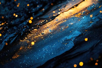 A close-up shot of a dark blue surface with glittering gold particles and a few out-of-focus yellow lights