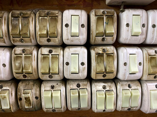 Group of old and dirty electrical white light switch mounted on old wooden wall. Unsafety home facility.