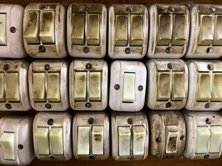 Group of old and dirty electrical white light switch mounted on old wooden wall. Unsafety home facility.