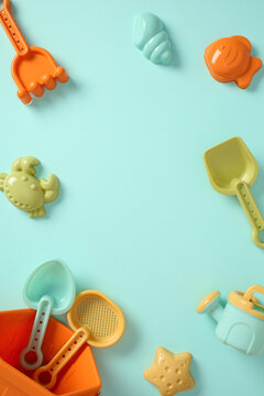 Colorful plastic beach toys frame on blue background with copy space