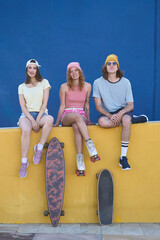 Group of young skaters posing with their skateboards and roller skates