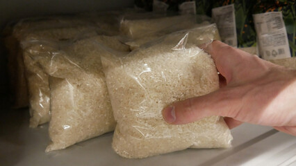 Close-up of a male hand taking a package of rice