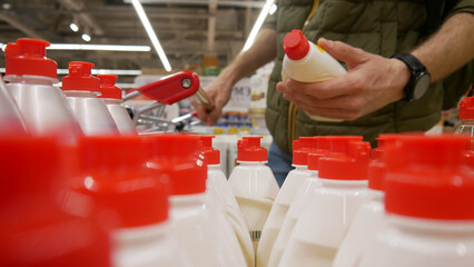 A male customer with a shopping trolley choosing dishwashing liquid