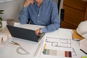 Asian Adult Architect Designs Building Blueprints Using Laptop for Site Plans Asian Adult Architect...