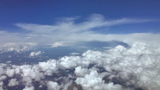 a pilot&rsquo;s view in a real time flight at very high altitude flying above storm clouds under an intense blue sky. 4K