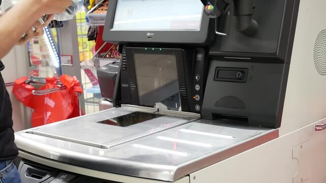 A young woman scanning food products at a supermarket self checkout