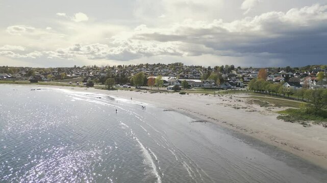 Aerial drone shot over Ringshaugstranda Beach near T&oslash;nsberg, Norway, with soft sunlight peeking through scattered clouds