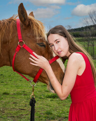 A young woman in a red dress with a horse