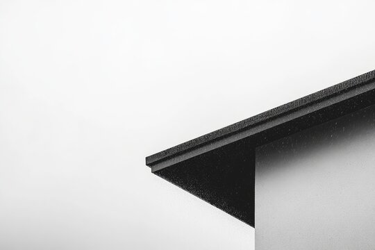 Close-up of a dark roof corner against a light-gray wall
