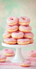 Pink frosted doughnuts stacked high on a white pedestal stand